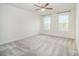 Spacious bedroom with plush carpet, two large windows, and a ceiling fan at 4604 Howie Ln, Harrisburg, NC 28075