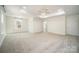 Spacious primary bedroom featuring plush carpet, tray ceiling with modern ceiling fan and large windows at 4604 Howie Ln, Harrisburg, NC 28075