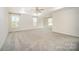 Spacious primary bedroom featuring plush carpet, tray ceiling with modern ceiling fan and large windows at 4604 Howie Ln, Harrisburg, NC 28075