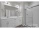 Bright bathroom featuring double vanity, large mirror, modern lighting, and tiled walk-in shower with glass door at 459 Shasta St # 5102, Gastonia, NC 28052