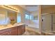 Bright bathroom featuring a dual sink vanity, large mirror, stylish lighting, soaking tub and walk-in shower at 5235 Reedy Ridge Rd, Charlotte, NC 28215