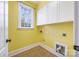 Bright laundry room with yellow walls, white cabinets, and tile flooring at 8105 Dumphries Dr, Huntersville, NC 28078