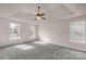 Bright main bedroom features neutral walls, plush carpet, tray ceiling and a ceiling fan with attached lighting at 9138 Babbitt Way, Charlotte, NC 28216