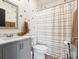 The bathroom is equipped with modern fixtures, gray vanity, neutral accents and a shower/tub with a striped curtain at 1017 Cheviot Ct, Waxhaw, NC 28173