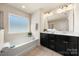 Bright bathroom features a soaking tub, a large window, and a double vanity with black cabinets at 113 Burlingame Ct # D, Mooresville, NC 28117
