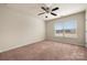 This bedroom features neutral walls, plush carpet, and a ceiling fan with a window for natural light at 113 Burlingame Ct # D, Mooresville, NC 28117