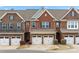 Charming brick townhome featuring attached garages and manicured landscaping under a bright blue sky at 113 Burlingame Ct # D, Mooresville, NC 28117
