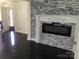 Living room with grey stone accent wall, black fireplace, and dark wood floors at 12662 Woodside Falls Rd, Pineville, NC 28134