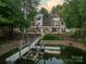 An aerial view of the property with a dock, lake, and beautifully landscaped backyard showcasing luxurious lake living at 129 Tuckernuck Dr, Mooresville, NC 28117