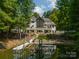 Back of home featuring a boat dock and lake access, surrounded by mature trees and lush greenery at 129 Tuckernuck Dr, Mooresville, NC 28117