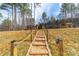 Picturesque backyard featuring a stone-lined path leading to a charming shed and pergola amid lush trees and foliage at 136 Falls Leaf Dr, Troutman, NC 28166