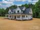 Stunning two-story modern farmhouse with a metal roof, covered porch, and landscaped front yard at 4024 Landsford Rd, Marshville, NC 28103