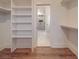 Spacious walk-in closet with white custom shelving leading into a bathroom with marble floors and shower at 4024 Landsford Rd, Marshville, NC 28103