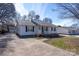 Single-story home featuring light gray siding, a front porch, and a long driveway leading to a detached garage at 403 Easy St, Concord, NC 28027