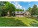 Expansive backyard with a lush lawn, mature trees, and a charming stone patio and fountain at 4531 Montibello Dr, Charlotte, NC 28226