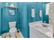 Bathroom features a toilet, vanity with mirror and a shelf above the toilet. Painted in a vibrant blue at 547 Lake Shore Dr, Norwood, NC 28128