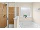 A bathroom featuring a bathtub, a glass shower, and a window for natural light at 6126 Castlecove Rd, Charlotte, NC 28278