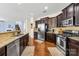 A kitchen with dark wood cabinetry, granite countertops, and stainless steel appliances at 6126 Castlecove Rd, Charlotte, NC 28278