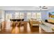 Open-concept living room with hardwood floors, a dining area, and large windows for natural light at 6126 Castlecove Rd, Charlotte, NC 28278