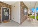Covered front porch with brick accents, a small bench swing, and a welcoming entrance door with sidelights at 6126 Castlecove Rd, Charlotte, NC 28278