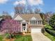 Inviting two-story home with a brick facade, dark shutters, and a well-manicured lawn with a beautiful, flowering tree at 6423 Red Maple Dr, Charlotte, NC 28277