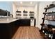 A modern basement bar featuring a countertop, black cabinets, floating shelves, and a small refrigerator at 12508 Asbury Chapel Rd, Huntersville, NC 28078