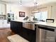 A modern kitchen featuring a large stainless steel farmhouse sink and a black kitchen island with white countertops at 12508 Asbury Chapel Rd, Huntersville, NC 28078