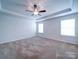Serene primary bedroom with tray ceiling, fan, neutral walls, and natural light at 15040 Cordelia Dr, Charlotte, NC 28278