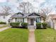 Charming white bungalow featuring blue accents, a welcoming porch, and lush green lawn at 1916 Pegram St, Charlotte, NC 28205