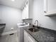 Functional laundry room with granite countertop, sink, white cabinets, and modern washer and dryer at 2217 Blue Bell Ln, Charlotte, NC 28270