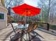 Outdoor dining on the deck with a large red umbrella, glass table, and wooded area at 2217 Blue Bell Ln, Charlotte, NC 28270