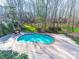Inground pool with surrounding patio, a black fence, and a wooded area at 2217 Blue Bell Ln, Charlotte, NC 28270