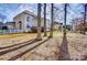 Large backyard partially fenced with mature trees and the back exterior of the home with a small deck at 2689 Wingrave Nw St, Concord, NC 28027
