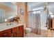 A well-maintained bathroom featuring a wooden vanity, tile flooring, and a shower-tub combo with a decorative curtain at 2689 Wingrave Nw St, Concord, NC 28027