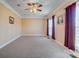 A bright bedroom featuring a ceiling fan, neutral carpet, and large windows with curtains for privacy and natural light at 2689 Wingrave Nw St, Concord, NC 28027