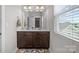 Bright bathroom with double sinks, a large mirror, dark wood cabinetry, and natural light at 3173 Delaware Dr, Denver, NC 28037