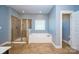A neutral-toned bathroom showcases a glass shower, a soaking tub beneath a window, and tile floors at 3173 Delaware Dr, Denver, NC 28037