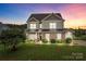 Charming two-story home boasts stone accents, a manicured lawn, and a welcoming front porch with dusk lighting at 3173 Delaware Dr, Denver, NC 28037