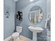 Stylish powder room with pedestal sink, decorative mirror, and blue accent wall at 3173 Delaware Dr, Denver, NC 28037