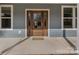Elegant wood front door with decorative glass panels, grey siding and concrete porch at 326 Lewis Ferry Rd, Statesville, NC 28677