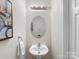 Small bathroom with a pedestal sink, an oval mirror, and an art piece on the wall at 3465 Caldwell Ridge Pkwy, Charlotte, NC 28213