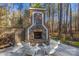 Inviting outdoor stone fireplace with Adirondack chairs for relaxing in a landscaped backyard at 4893 River Hills Dr, Denver, NC 28037