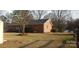 Home's brick exterior with a grassy yard, pine straw, green bushes, and a few trees at 501 Catawba N Cir, Matthews, NC 28104