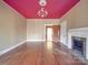 Spacious living room with hardwood floors, fireplace, chandelier, and an eye-catching red ceiling accent at 505 Camden Rd, Wadesboro, NC 28170