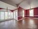 Open living room features hardwood floors, large windows, and is painted with a vibrant, deep red at 505 Camden Rd, Wadesboro, NC 28170