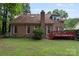 Back exterior of a brick home with a well-maintained lawn and small outdoor wooden deck at 8731 Sheltonham Way, Charlotte, NC 28216