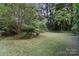 Lush backyard with mature trees and a well-manicured lawn at 8731 Sheltonham Way, Charlotte, NC 28216
