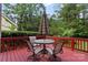 Red painted wooden deck with a patio table and four chairs with trees in the background at 8731 Sheltonham Way, Charlotte, NC 28216