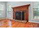 Classic brick fireplace framed by hardwood floors and bright windows with white shutters at 8731 Sheltonham Way, Charlotte, NC 28216
