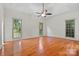 Spacious main bedroom with hardwood floors, ceiling fan, and three windows at 8731 Sheltonham Way, Charlotte, NC 28216